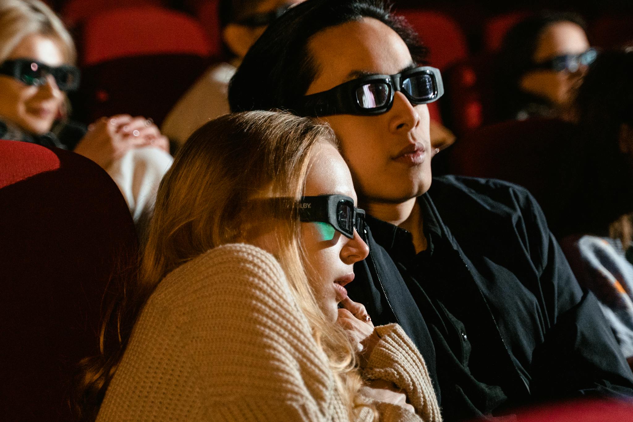 A couple immersed in a 3D movie experience at the cinema, enjoying a thrilling film.
